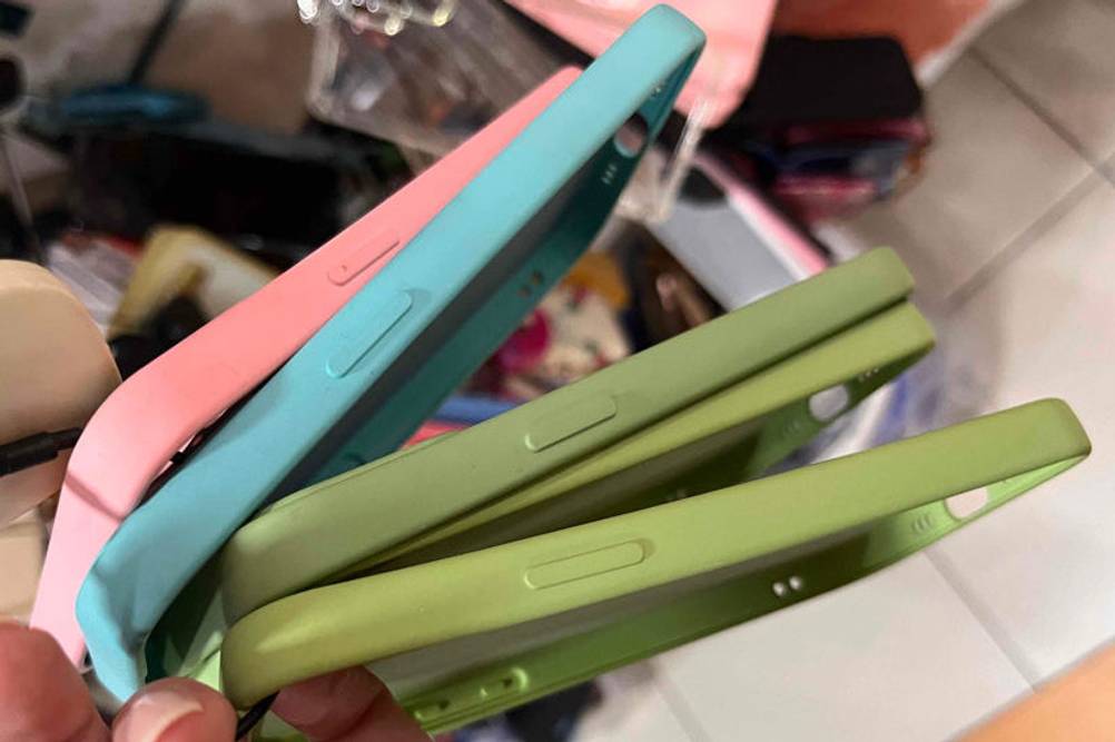 Iphone-12-pro-max-Hülle getestet: verschiedene Handyhüllen auf einem Bunt werden in der Hand gehalten.