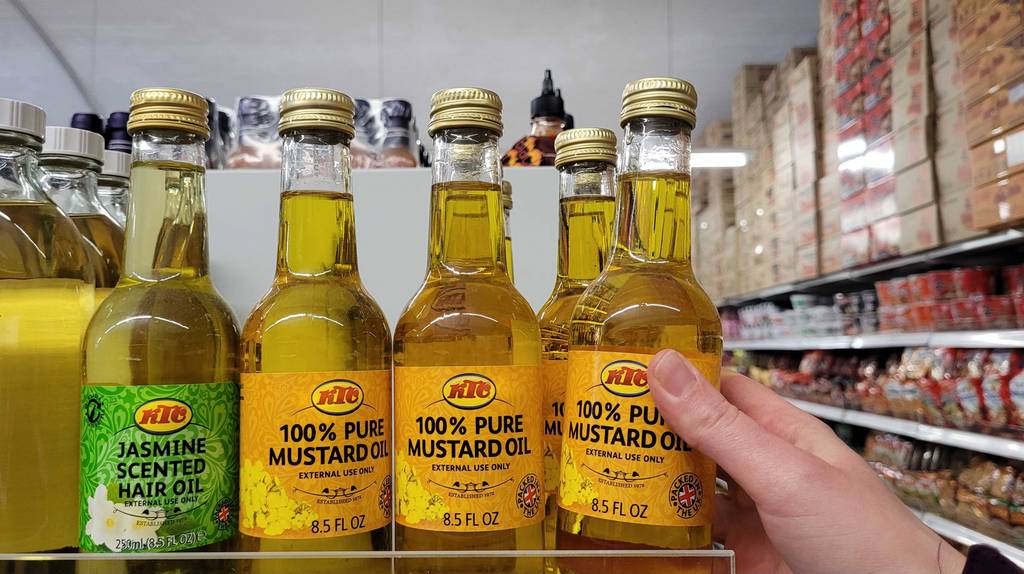 Senföl getestet: mehrere Senföle in einem Regal stehend, während eines entnommen wird.