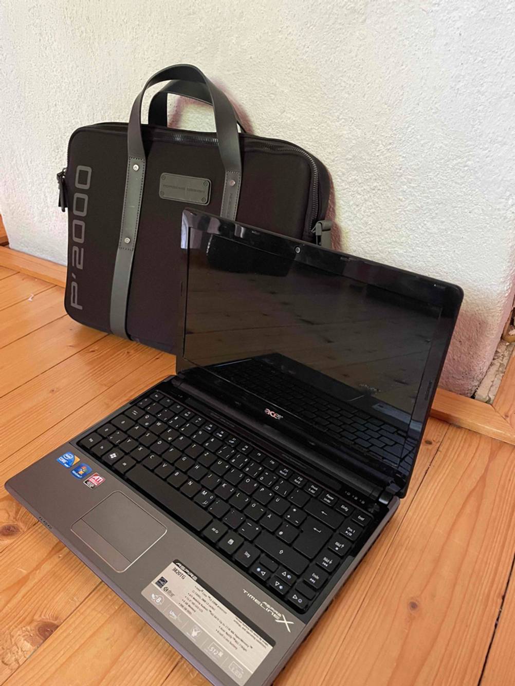 Im Test: Eine Laptoptasche lehnt an der Wand im Vordergrund steht ein Laptop.