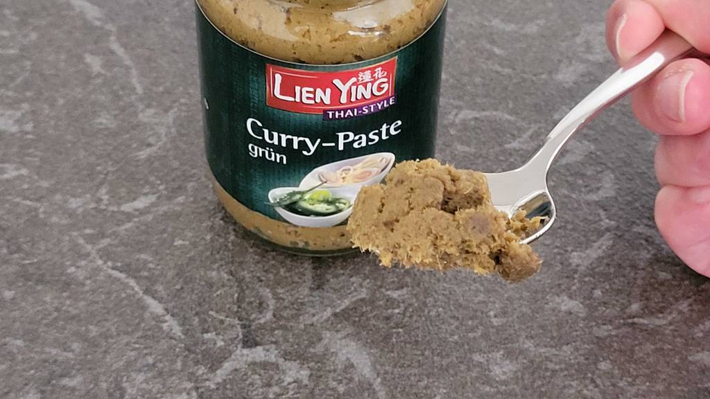 Currypaste getestet: Ein Löffel voll Paste vor einem Glas Paste