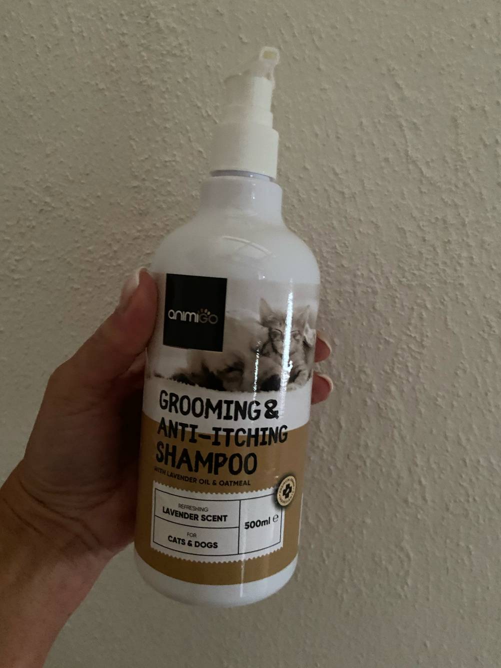 Das getestete Milben-Shampoo für den Hund wird in der Hand vor einer weißen Wand gehalten.
