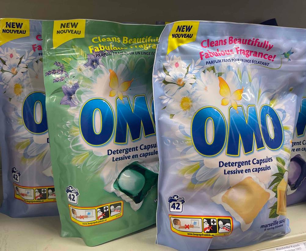 Mehrere getestete Omo-Waschmittel stehen aufgereiht in einem Regal.