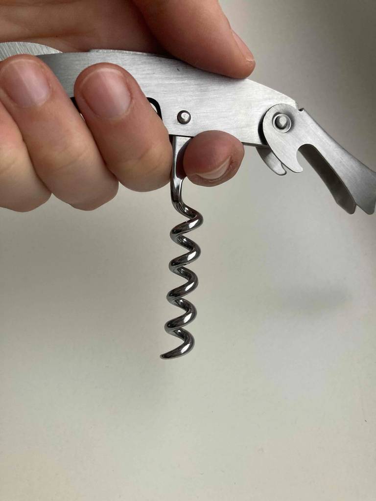 Kellnermesser getestet: Eine Hand hält ein Gerät mit Korkenzieher nach unten.