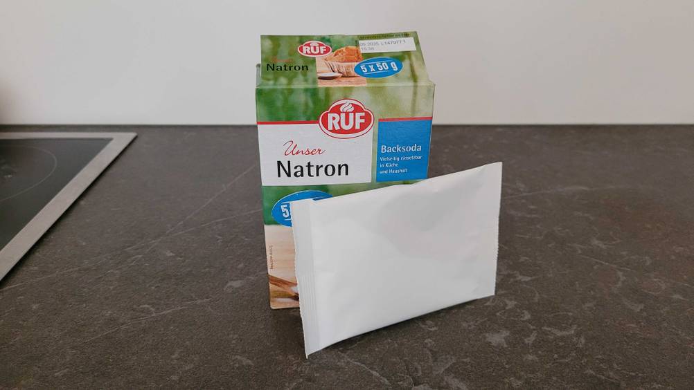 An einer Schachtel Natron lehnt ein einzelnes Päckchen.