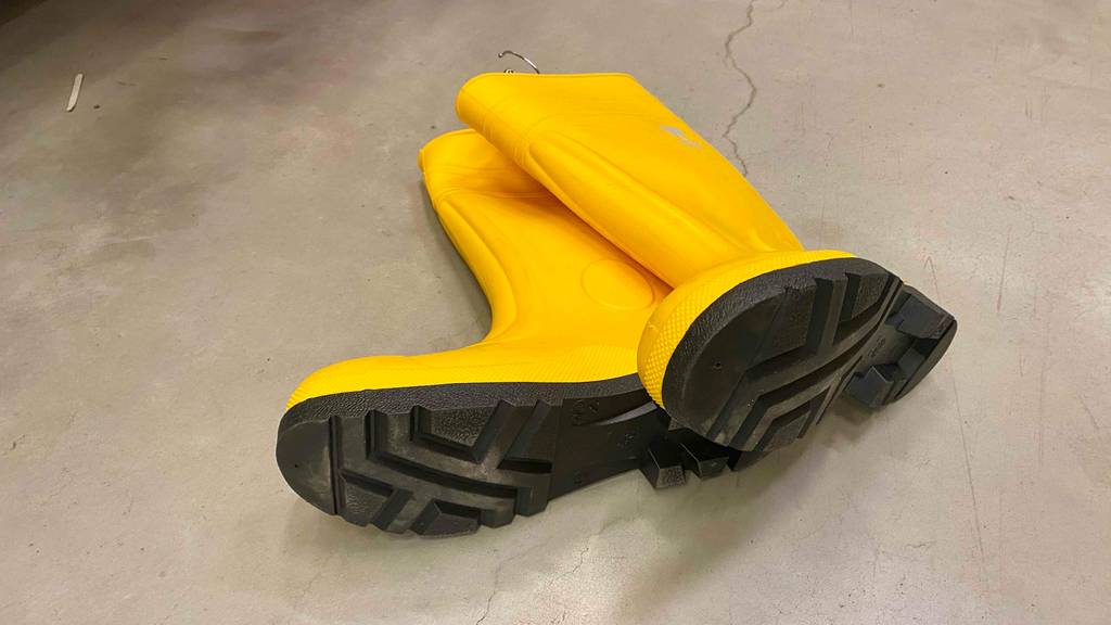 Gummistiefel-Herren-Test: ein Paar gelbe Gummistiefel auf einem Boden liegend mit Blick auf die Sohlen.