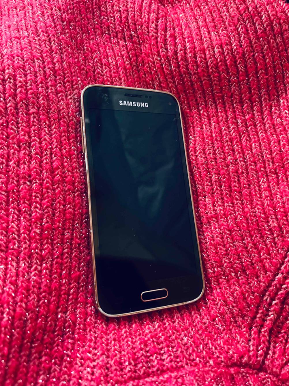 Ein getestetes kleines Smartphone liegt auf einer pinken Stofffläche.