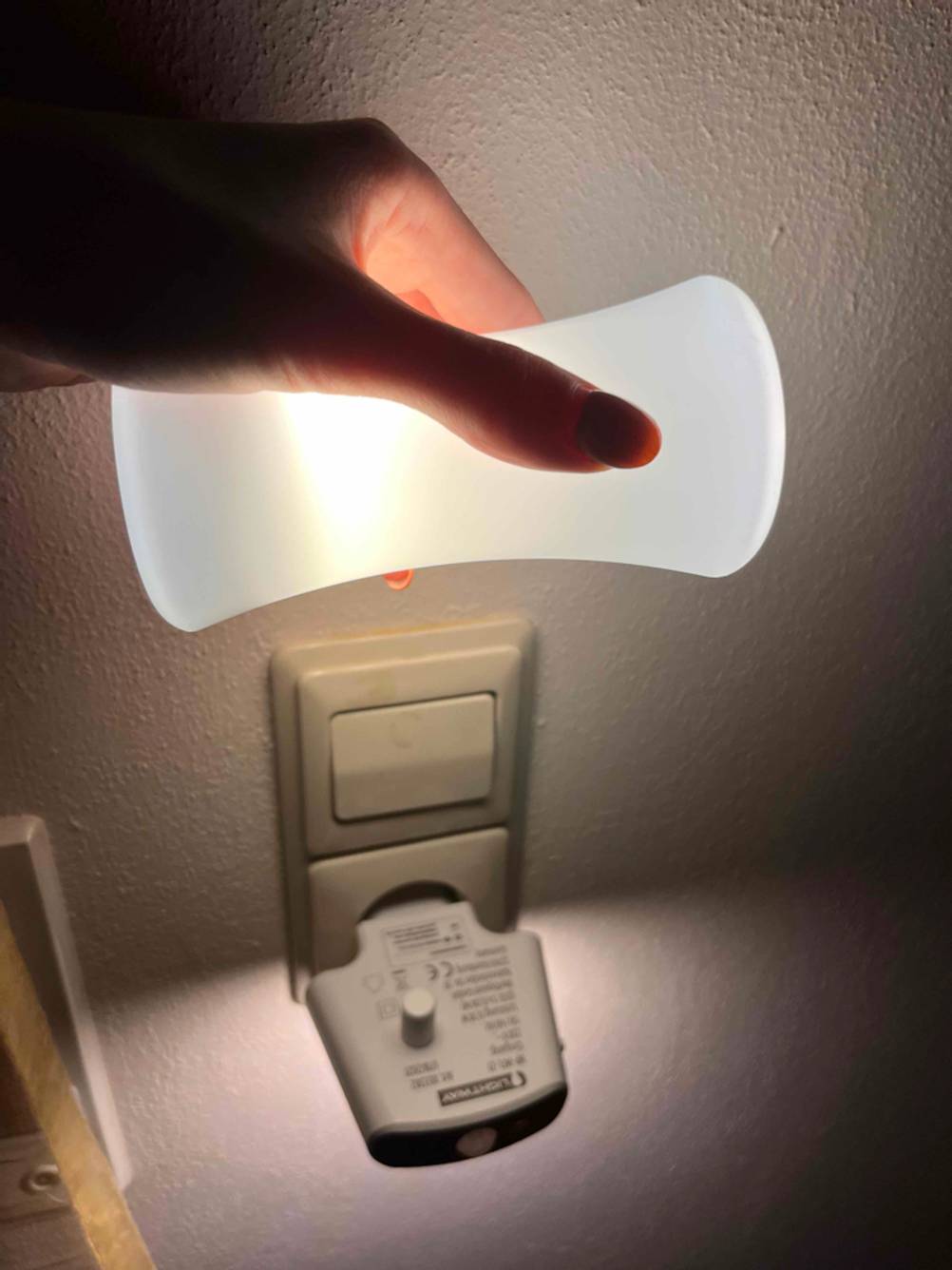 Stilllicht getestet: Eine Hand steckt ein Stilllicht in eine in der Steckdose steckende Befestigung.