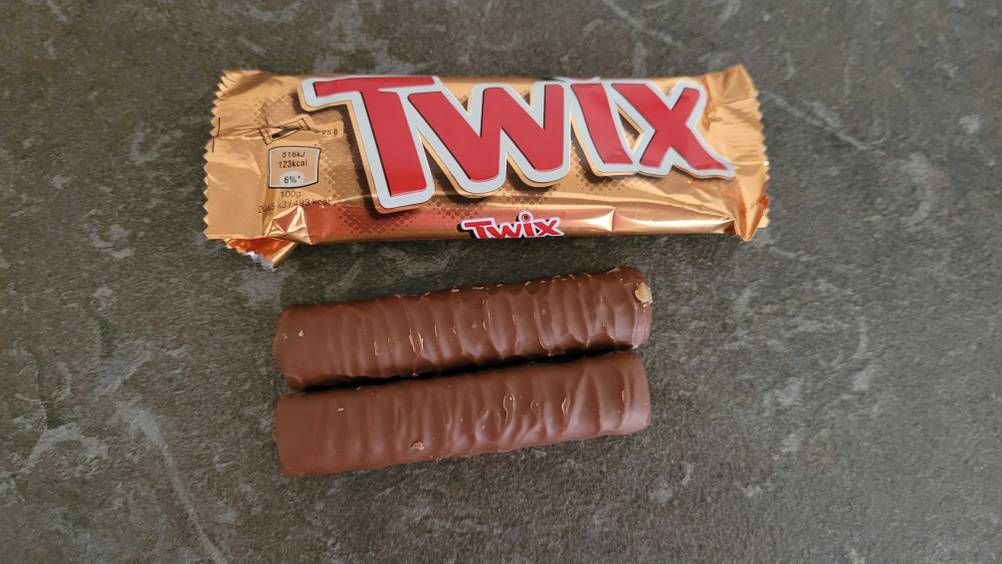 Schokoriegel getestet: Zwei Riegel neben ihrer Originalverpackung auf einer dunklen Fläche.