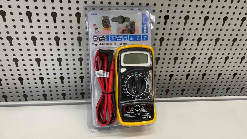 Im Test: Ein Multimeter lehnt an einem Lochblech auf einer hellen Fäche.