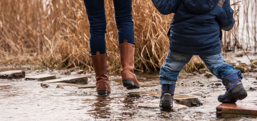 Die beschuhten Füße einer Frau und eines Kindes im strömenden Regen