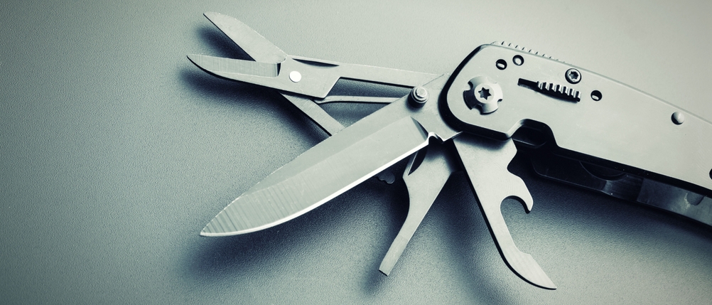 Ausgeklappte Werkzeuge eines Multitools vor grauem Hintergrund