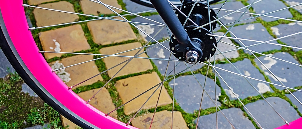 Ein Fahrradreifen wurde auf eine pinke Felge aufgezogen und steht auf Pflastersteinen.