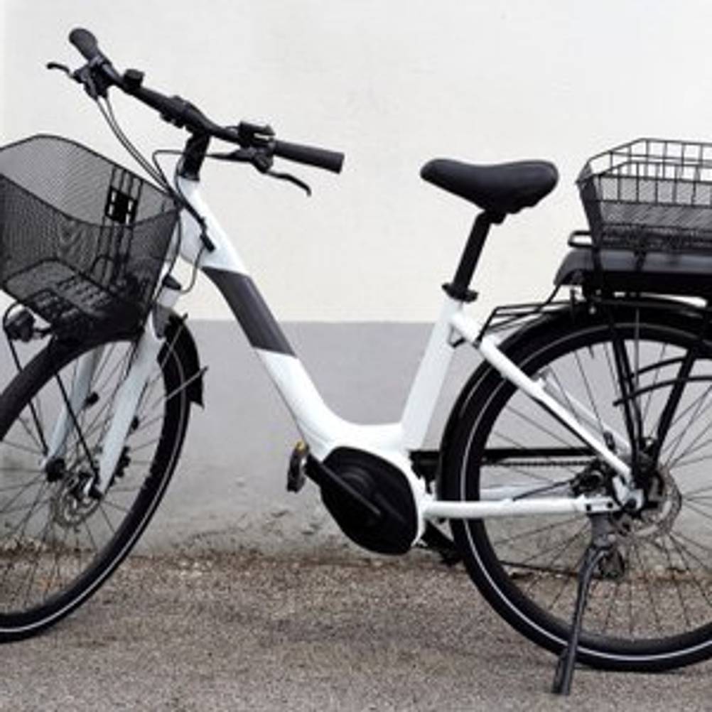 Schwarz-weißes E-Bike mit Fahrradkorb vorne und Fahrradkorb hinten