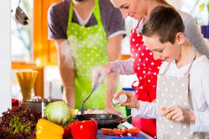 Family cooking healthy food in domestic kitchen