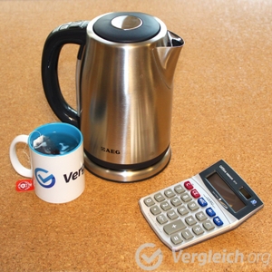Wasserkoche steht neben einer Teetasse und einem Taschenrechner.