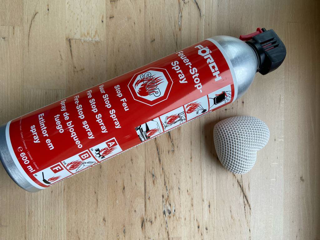 ABF-Feuerlöscher im Test: Nahaufnahme eines Feuer-Stop-Sprays in einem roten 600-ml-Druckbehälter, der neben einem weißen Dekoherz liegt.