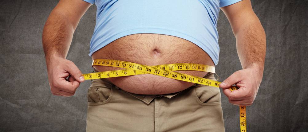 Abnehmprogramme im Test: Ein Mann mit Bierbauch misst seinen Bauchumfang.