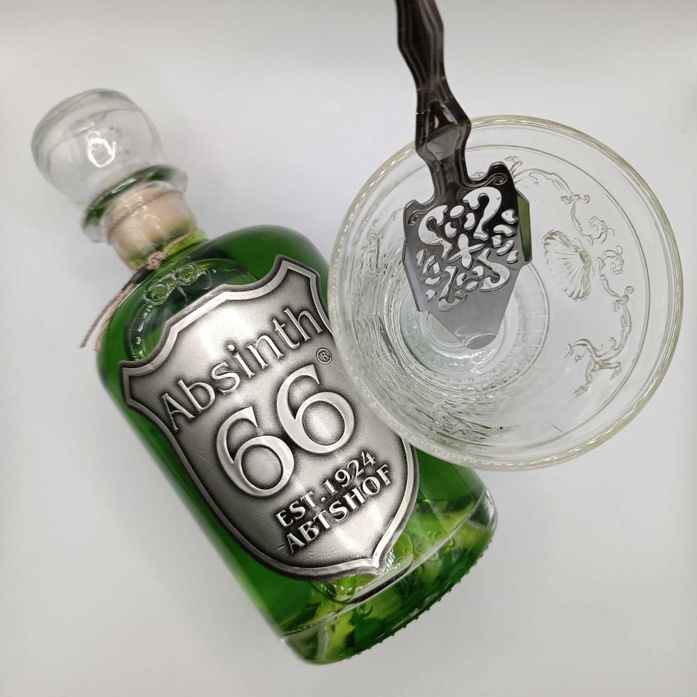 Absinth getestet: Eine Flasche liegend neben einem Glas auf einer hellen Fläche.