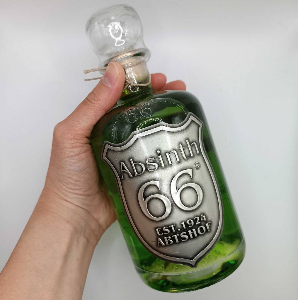 Absinth im Test: Eine Hand hält eine Flasche Absinth vor eine helle Wand.