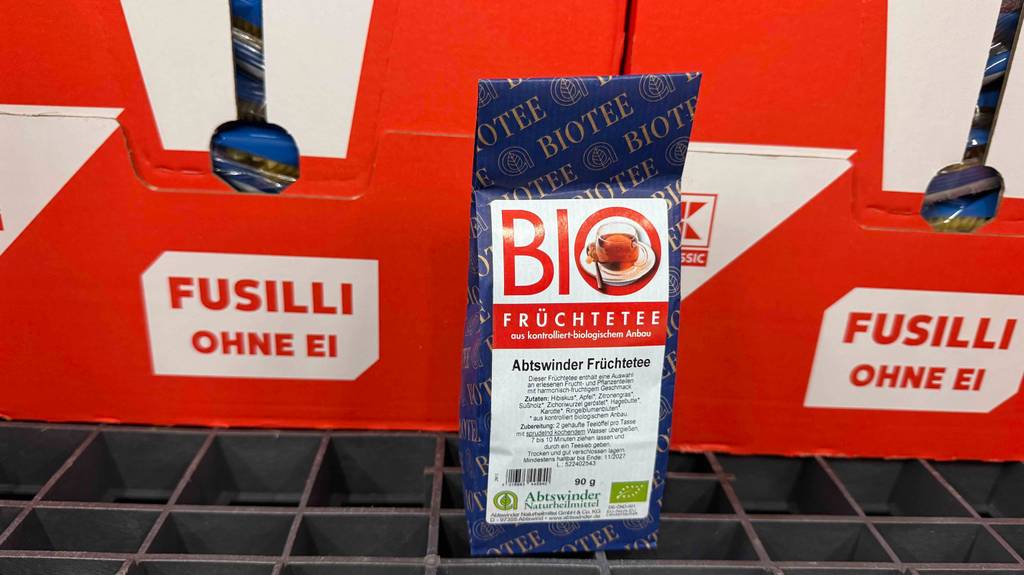 Getesteter Bio-Früchtetee aus kontrolliert biologischem Anbau befindet sich in einem 90-g-Beutel, der vor Kaufland-Kartons mit Nudeln steht.