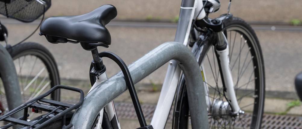 Abus Bügelschloss Test: Ein Fahrrad ist mit einem Bügelschloss an einem massiven Fahrradständer angesperrt.