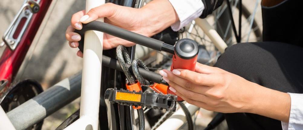 Abus Bügelschloss Test: Eine Frau legt an einem Fahrrad ein Bügelschloss an.