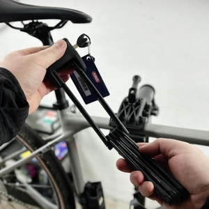 Das Abus-Faltschloss Bordo 6000K wird mit beiden Händen aufgeklappt. Der Schlüssel hängt am Schloss.