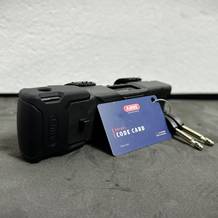 Das Abus Bordo 6000K liegt auf einer Fläche. Daneben befinden sich zwei Schlüssel und eine XPlus Code Card.