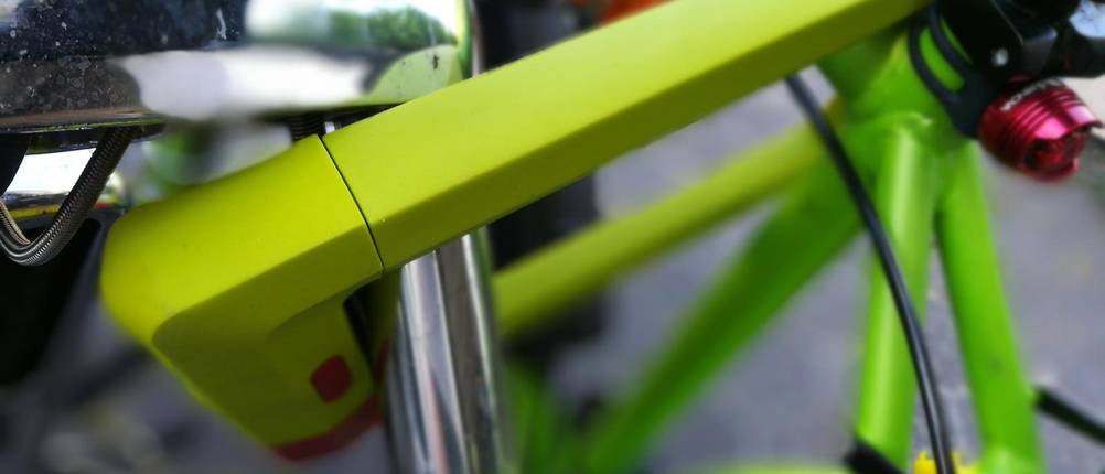 Abus Bügelschloss Test: Ein giftgrünes Bügelschloss sichert ein Fahrrad. Nahaufnahme.