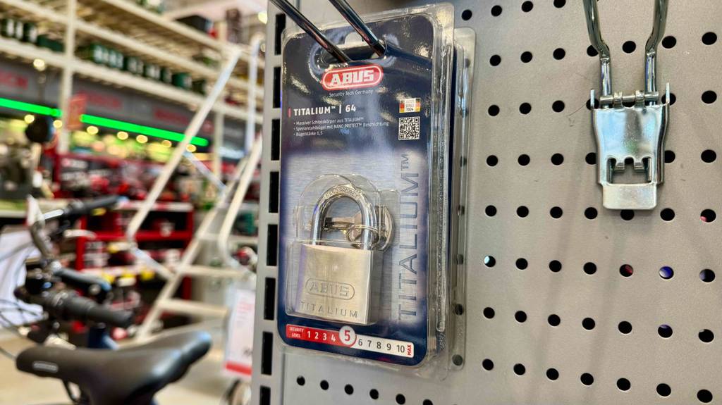Ein verpacktes Abus-Vorhängeschloss hängt zum testen in einem Regal.