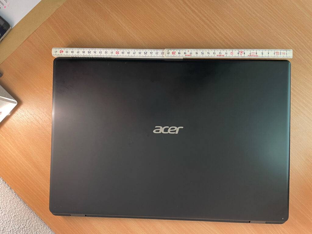 Bick von oben auf ein zugeklapptes Laptop bis 1000 Euro, darüber zeigt ein Meterstab die Breite an.