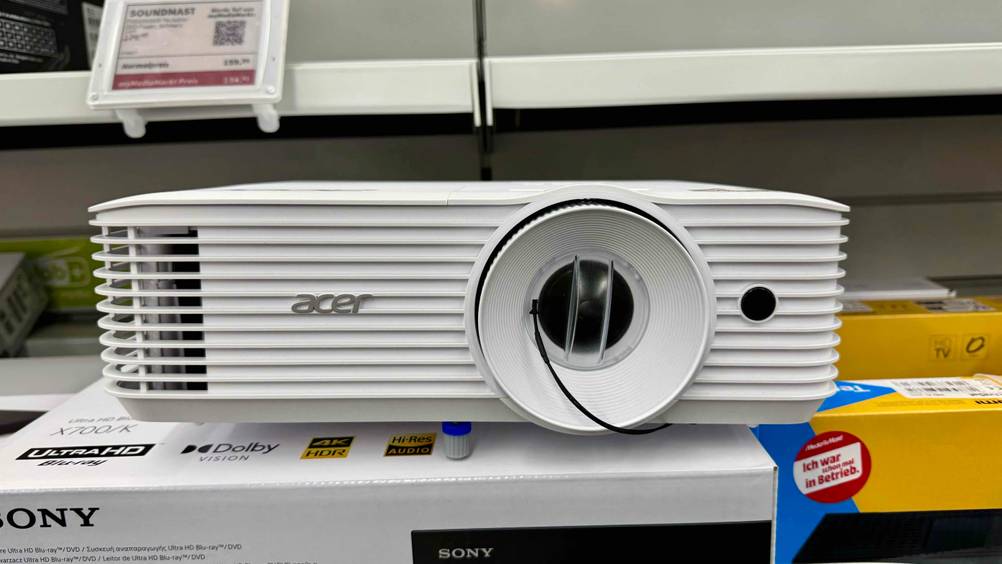 Der Acer-Beamer im Test von vorne auf einem Karton stehend.