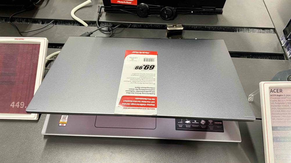 Ein getestetes 17-Zoll-Laptop leicht zugeklappt von oben auf einer dunklen Verkaufsfläche stehend.
