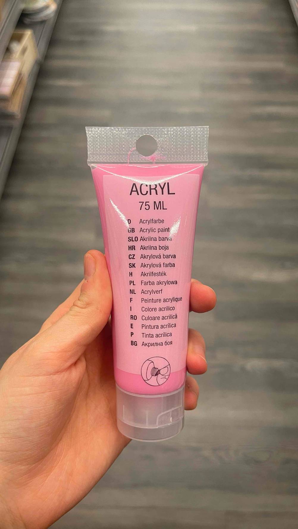 Acrylfarben im Test: Eine Hand hält eine Tube in pinker Farbe.