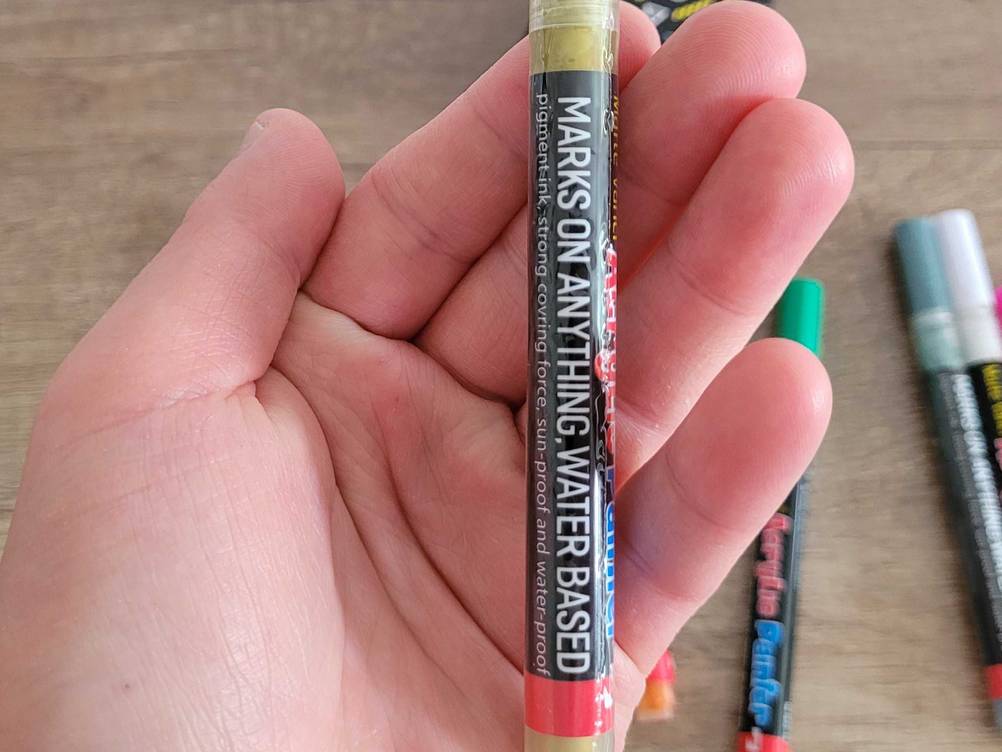 Eine Hand hält einen Acrylstifte im Test, Fokus auf den Aufdruck.