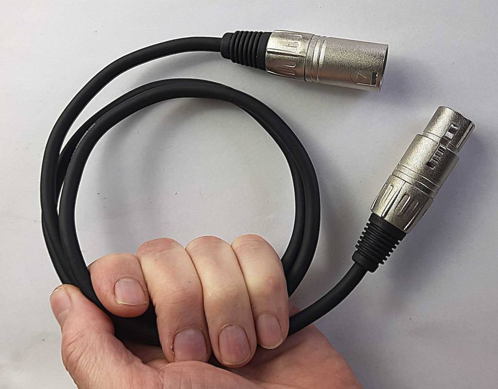 Im Test: Das Audiokabel in Schwarz inklusive versilberter Stecker befindet sich aufgerollt in einer Hand vor weißem Hintergrund.