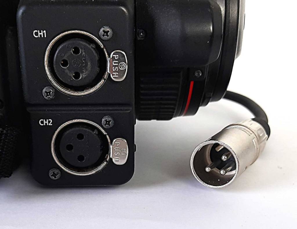 Der dreipolige, versilberte Stecker am schwarzen Audiokabel im Test liegt neben der Audiobuchse eines elektronischen Geräts.