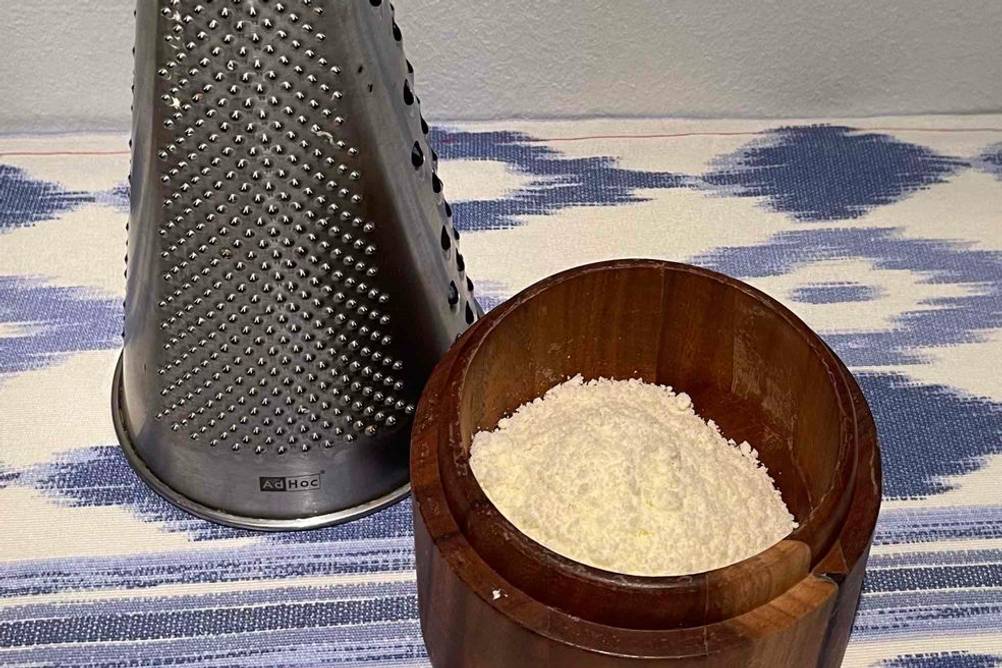 Parmesanreibe im Test: Eine Reibe stehen hinter einer Schüssel mit geriebenem Parmesan.