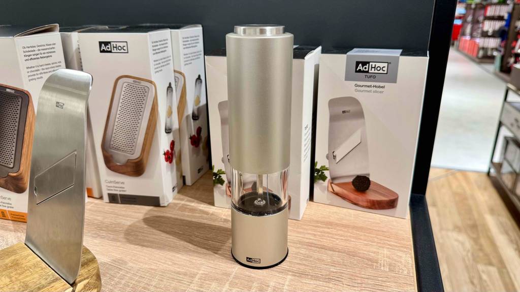 Im Test: Eine graue AdHoc-Pfeffermühle steht in einem Regal zwischen anderen Haushaltsgeräten.