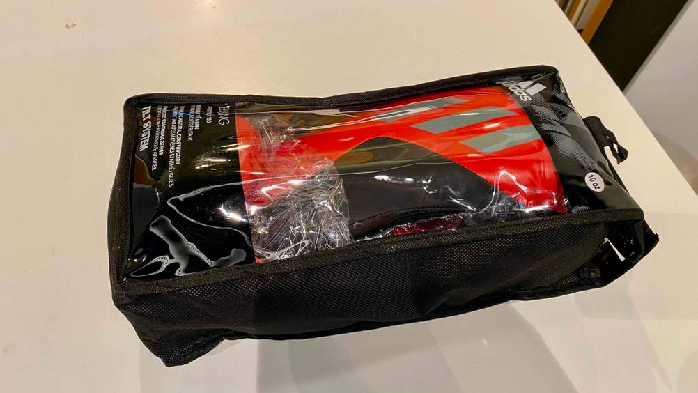 Adidas Boxhandschuhe im Test: ein schwarz-rotes Modell liegt in seiner schwarzen Verpackung inklusive Sichtfenster auf einem weißen Untergrund.