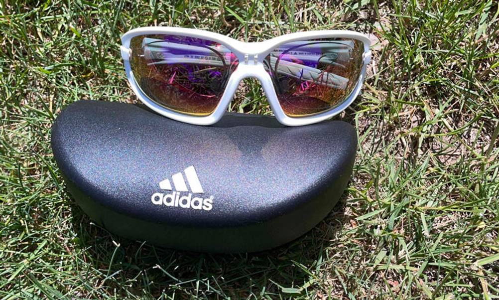 Getestet: Eine Fahrradbrille für Brillenträger, gegen Sonneneinstrahlung, liegt zusammengelegt auf einem ADIDAS-Brillenetui, das sich auf dem Rasen befindet.