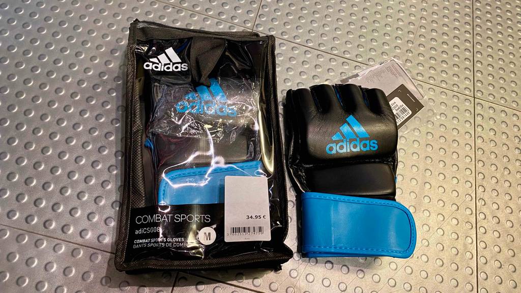 MMA-Handschuhe getestet: Ein Handschuh neben seiner Originalverpackung auf einer silbernen Fläche mit Noppen.
