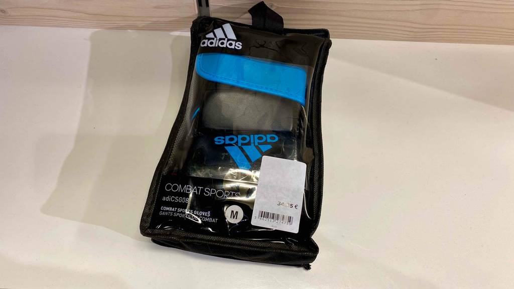 Getestete MMA-Handschuhe in ihrer Originalverpackung mit transparentem Sichtfenster auf einer hellen Fläche.