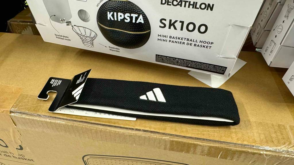 Stirnband-Test: Ein schwarzes Modell der Marke ADIDAS liegt auf einem Karton vor einer Football-Verpackung.