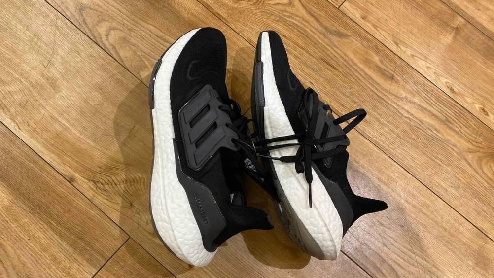 Ein Paar getestete Adidas-Ultra-Boost auf der Seite liegend auf einem Holzboden.