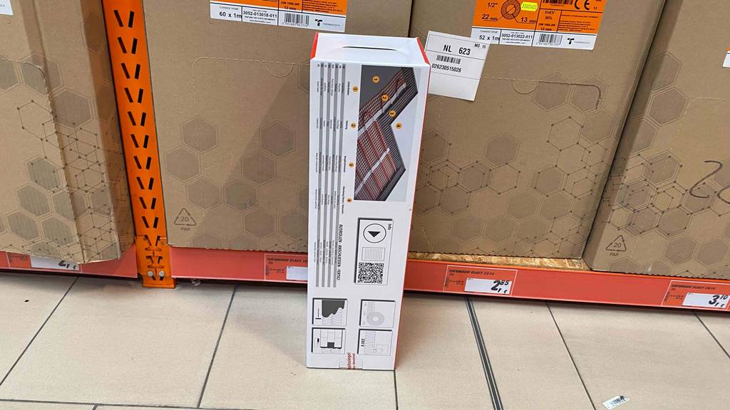 Elektrische Fussbodenheizung im Test: ein Verpackungskarton steht hochkant vor einem Regal.