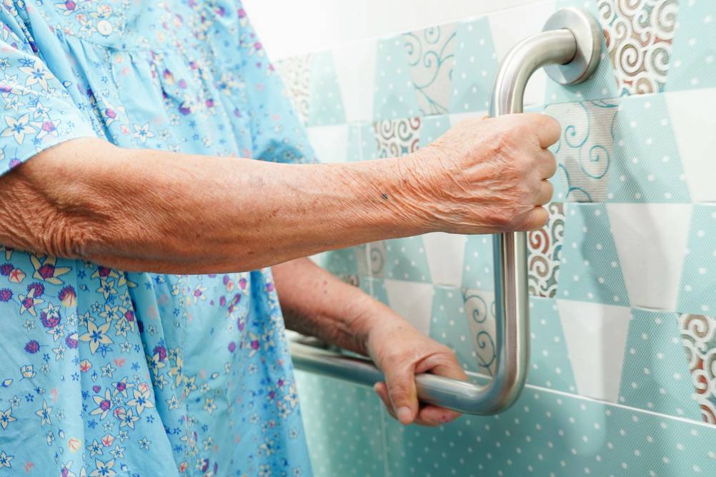 Badewannenlift im Test: Sensiorin hält sich an einem Griff im Badezimmer fest.