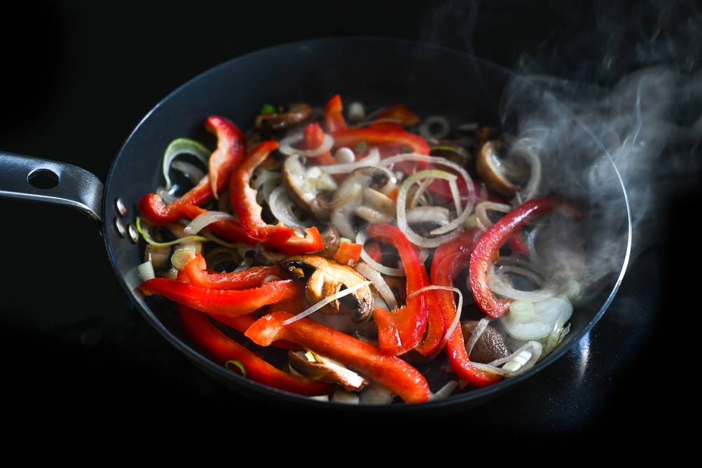 Caso-Induktionskochfeld im Test: Paprika, Zwiebeln und Pilze in einer dampfenden Pfanne auf dem Kochfeld