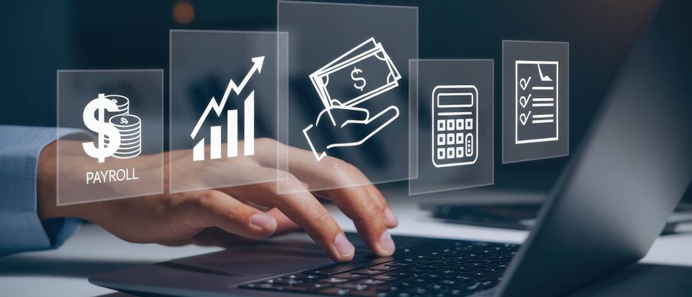 Die beste Banking-Software im Vergleich: Eine Person tippt etwas in einen Laptop, über der Hand erscheinen verschiedene Symbole, welche die Funktionen einer Banking-Software repräsentieren.