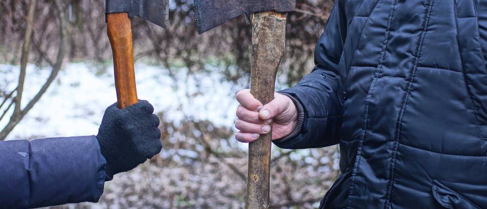 Handbeil im Test: Je eine Person hält ein Handbeil und eine Axt in einer Gegenüberstellung fast Klinge an Klinge.